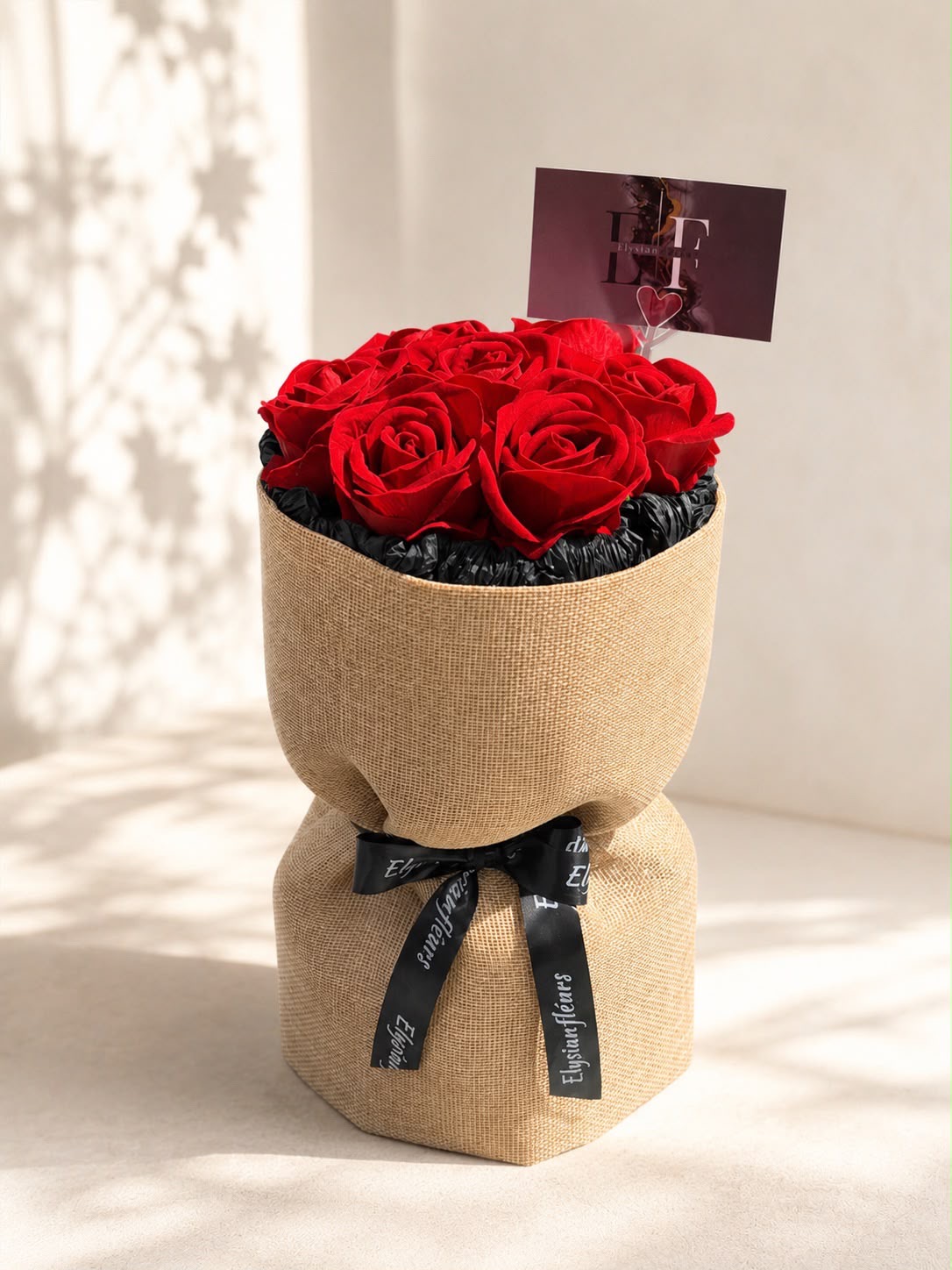 Red roses in signature burlap wrap with Elysian Fléurs card