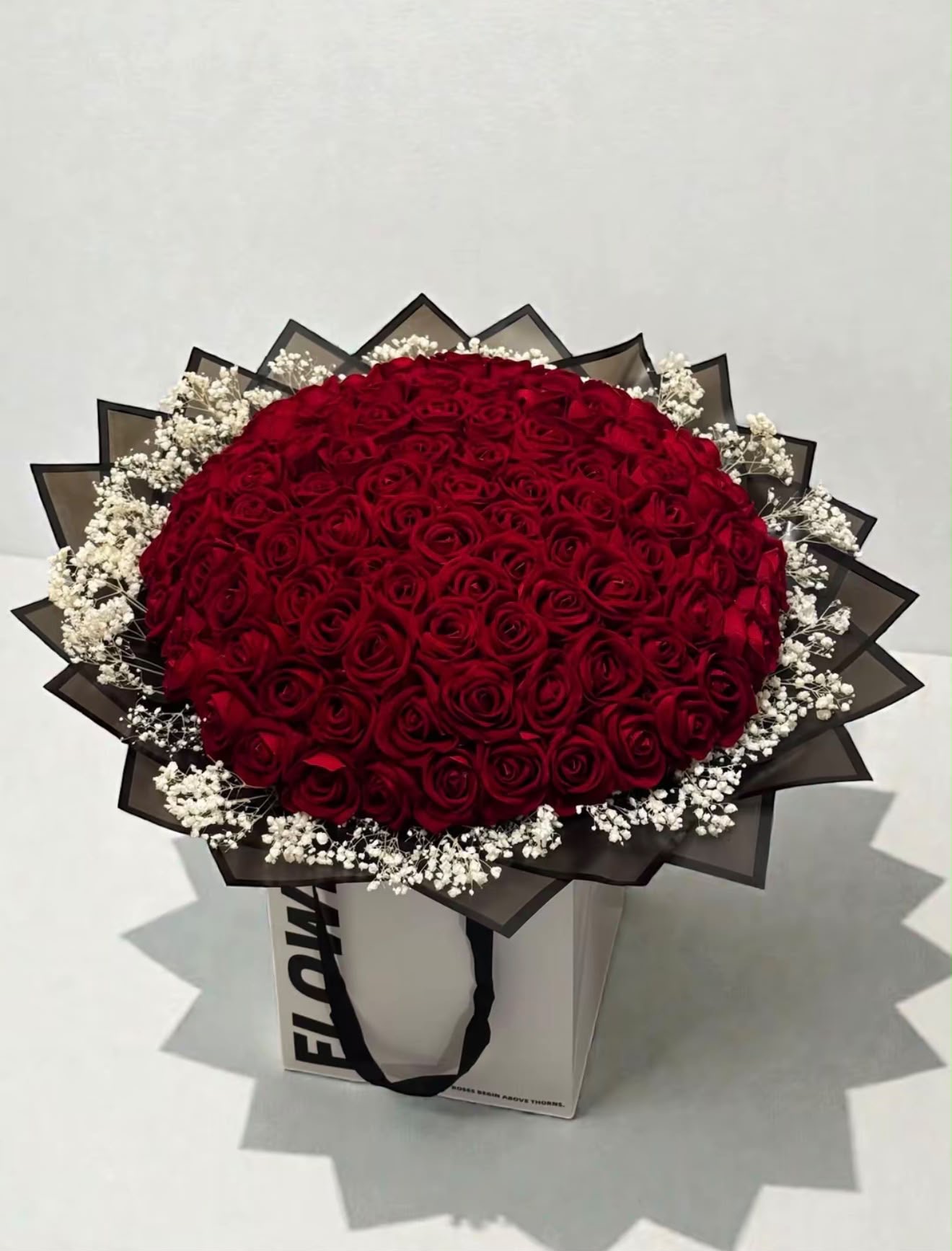 Signature round red rose bouquet framed with baby's breath and black organza