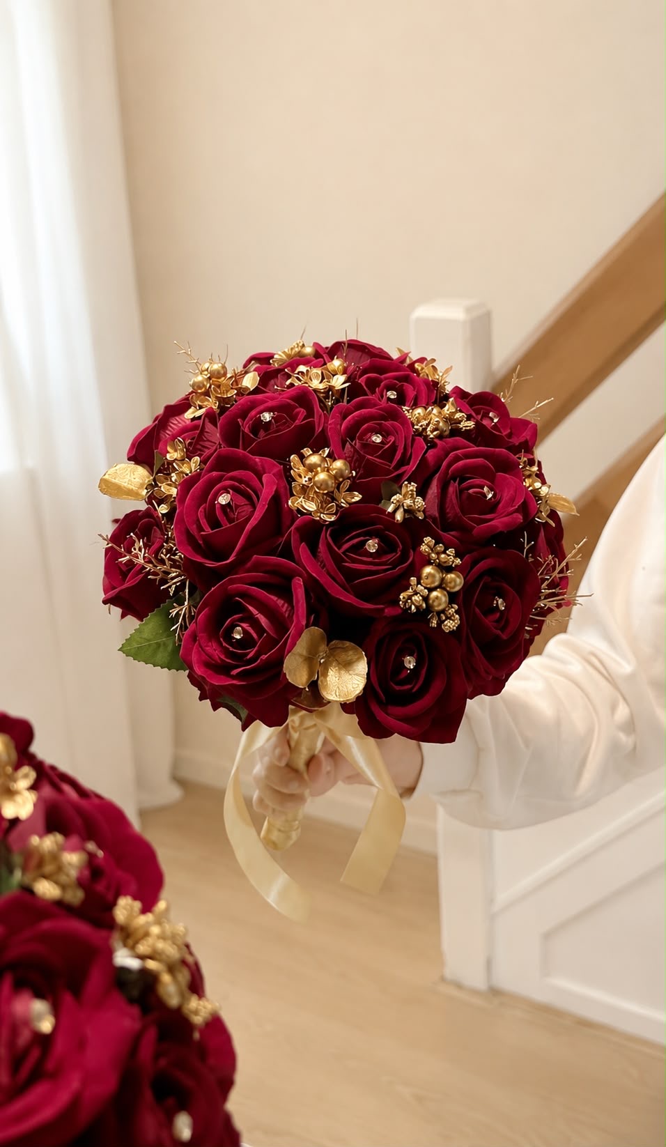 Bridal bouquet of burgundy roses with gold accents and ivory ribbon