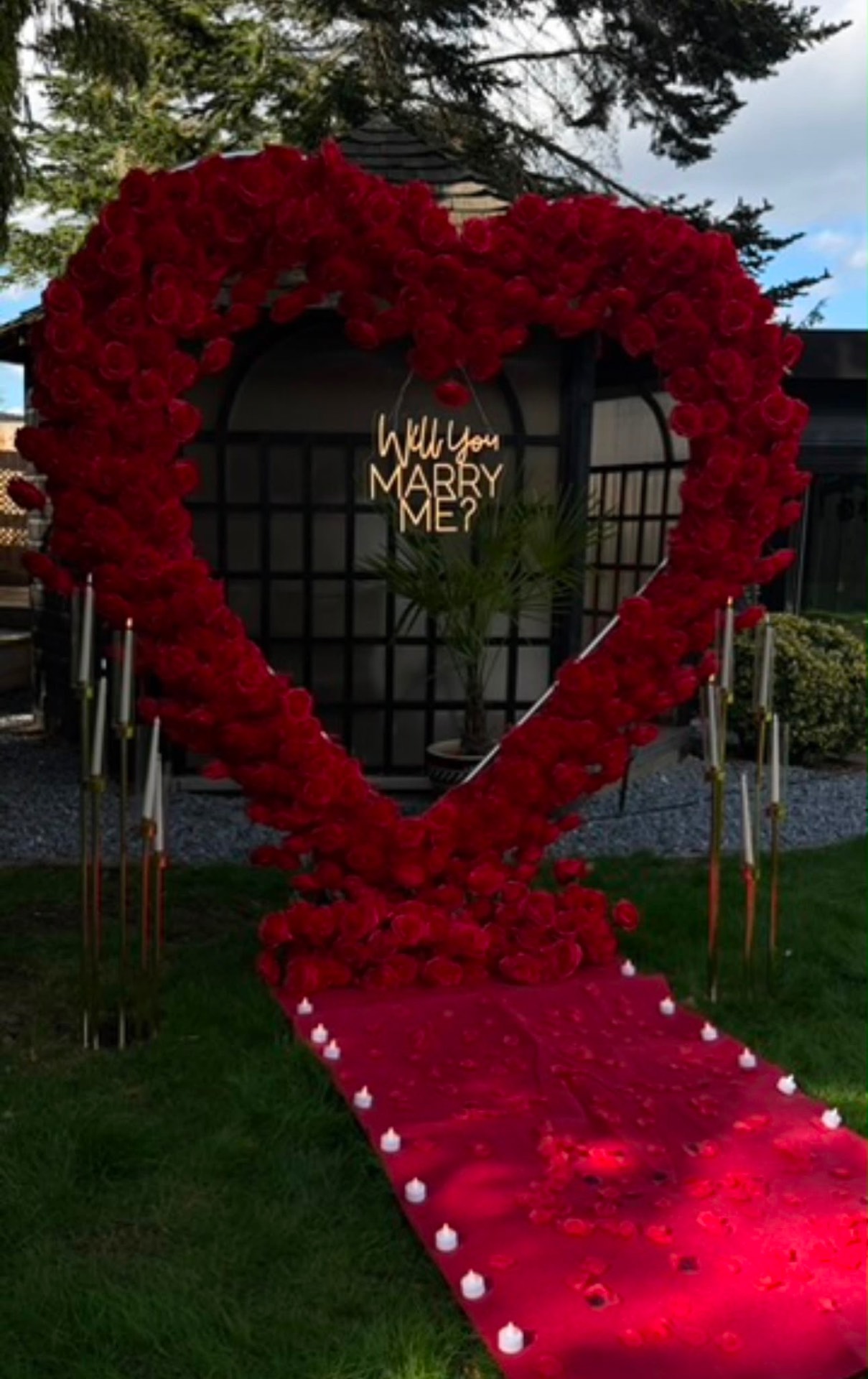 Outdoor proposal rose heart with candlelit red carpet