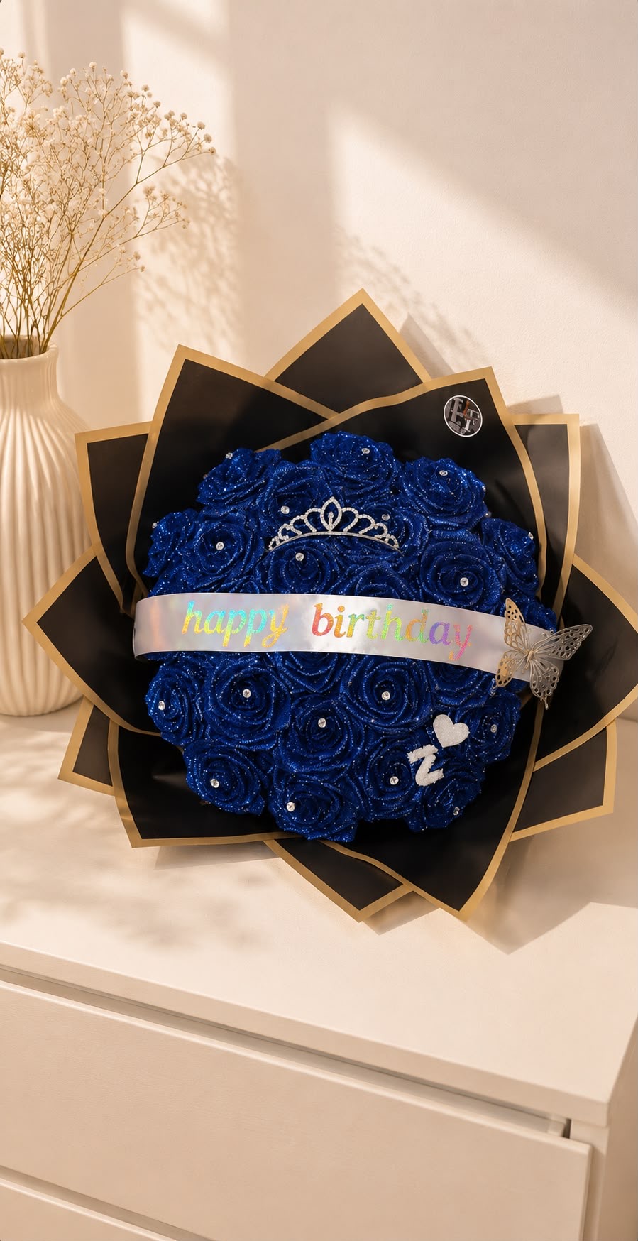 Royal blue glitter rose birthday bouquet with tiara, butterfly and 'Happy Birthday' banner in black and gold fan wrap