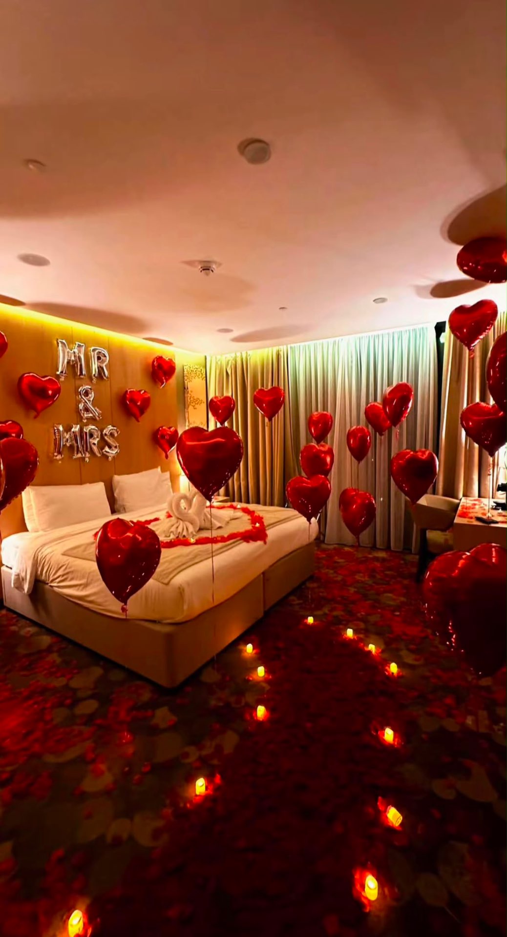 Mr & Mrs wedding suite with red heart balloons, rose petals and candlelight