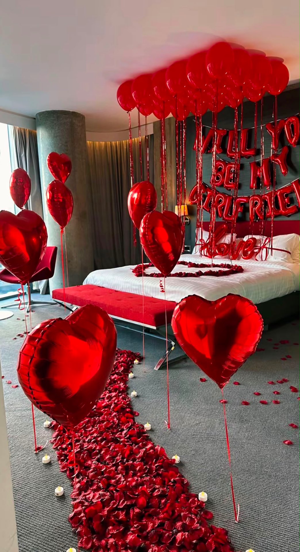 Will You Be My Girlfriend proposal with red balloon canopy, heart balloons and a rose petal aisle lit by candles
