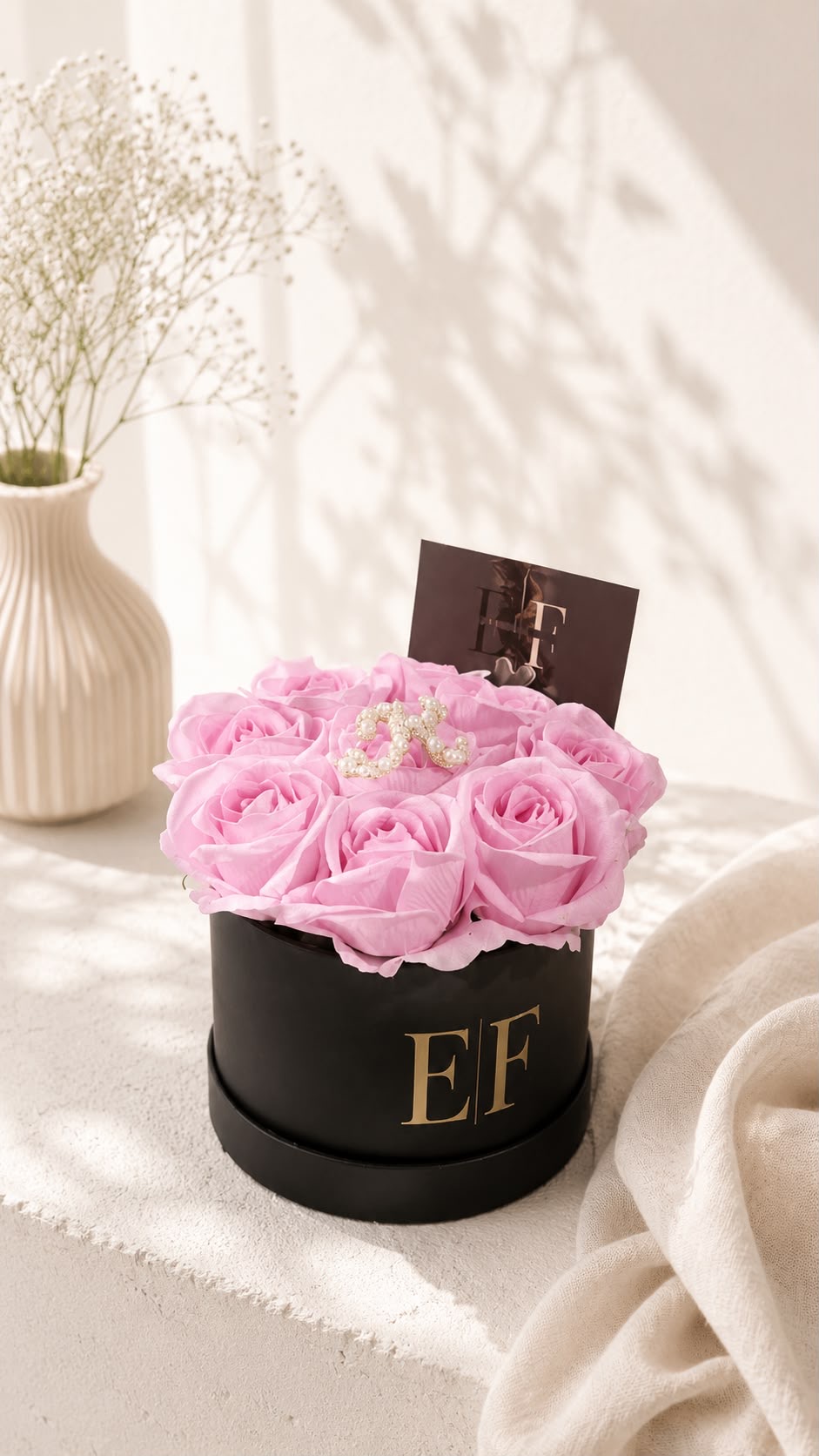 Blush pink preserved roses in a black EF hat box with pearl monogram initial 'R'