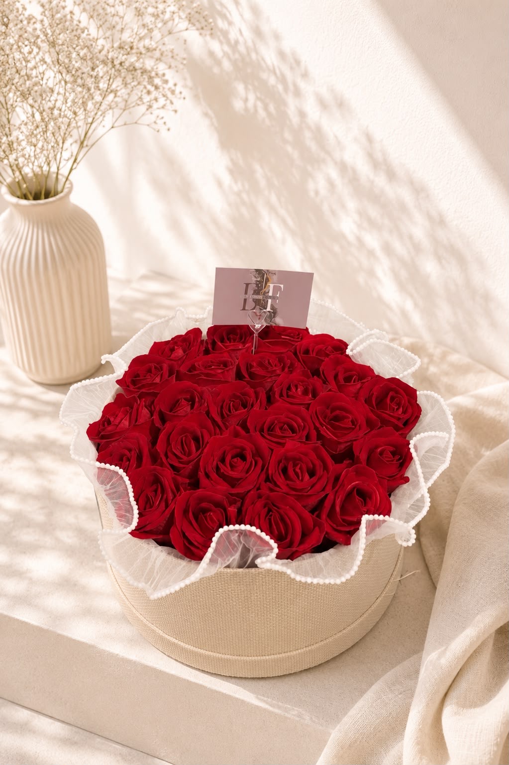 Round arrangement of preserved red roses in a natural burlap box with pearl-trimmed organza and EF card
