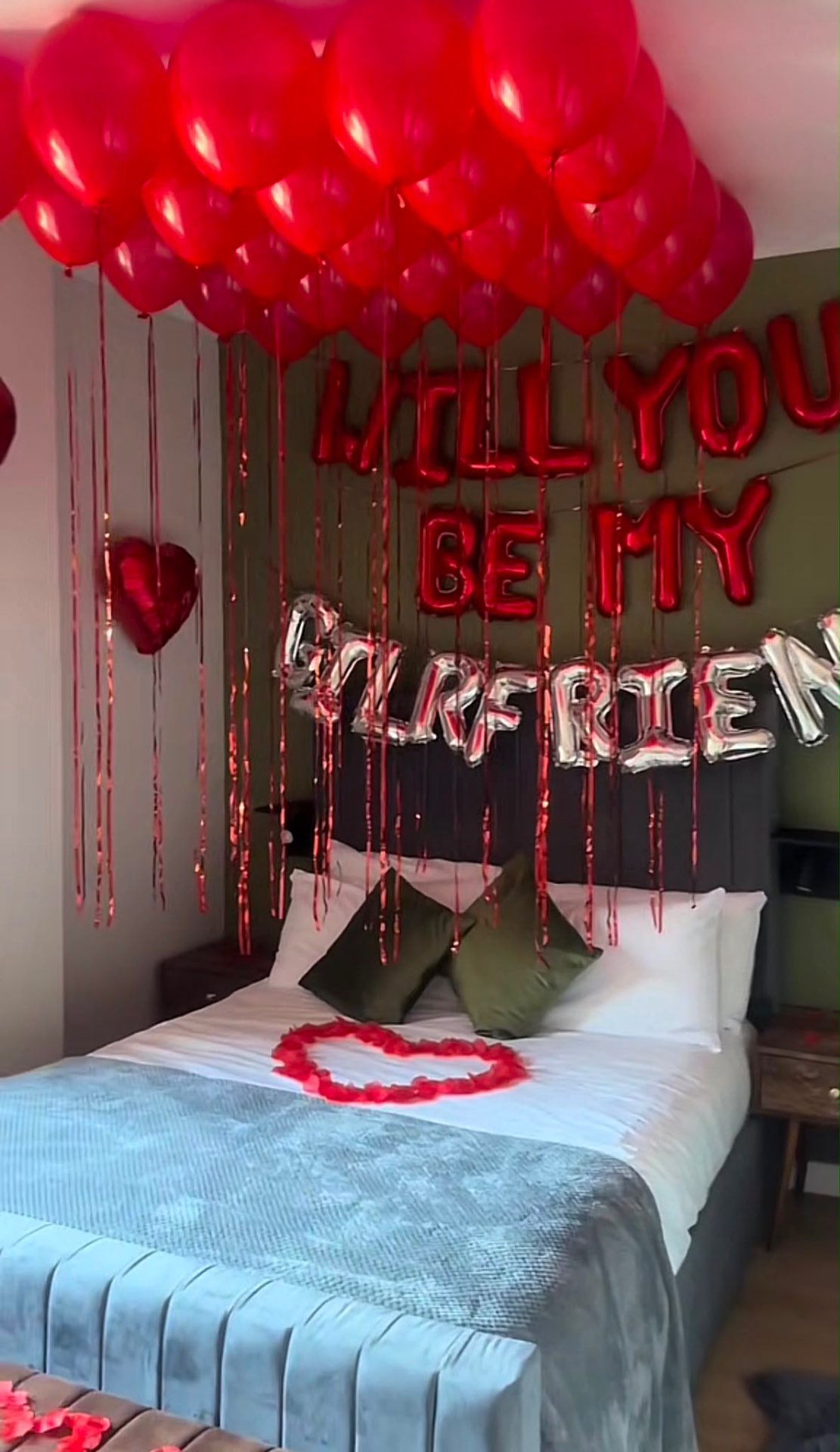Will You Be My Girlfriend proposal with red balloon ceiling and heart of petals